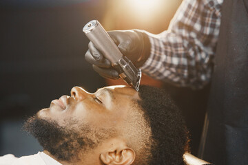 Young African-american man visiting barbershop - Powered by Adobe