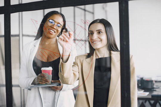 Businesswoman talking and writing on transparent board at modern office