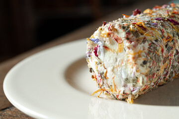 Fresh french goat cheese with honey and flowers on the light plate close-up
