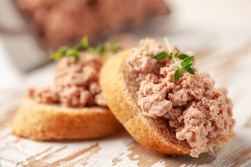Fresh homemade goose liver pate on toasted bread with greens and capers.