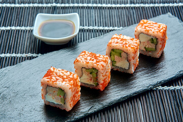 Philadelphia roll classic with red caviar on a dark stone on the board. Japanese sushi.