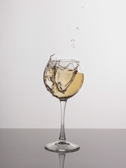 Splashes of white wine on a white background on the glass