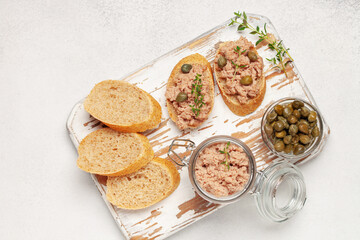 Fresh homemade goose liver pate on toasted bread with greens and capers. Top view