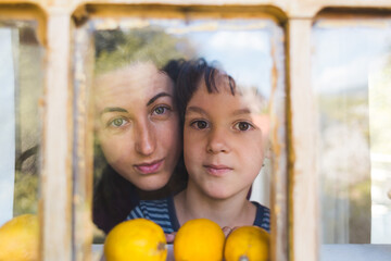 Obraz premium A boy with his mother curiously peeks out the window of a wooden house.