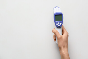 Female hand with infrared thermometer on white background