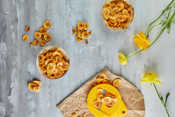 Banana chips healthy food, dry fruits and healthy vegetable chips, healthy vegan snack on background of yellow flowers