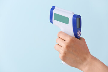 Female hand with infrared thermometer on color background