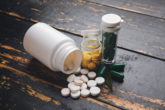 Bottles with different pills on dark wooden background, closeup
