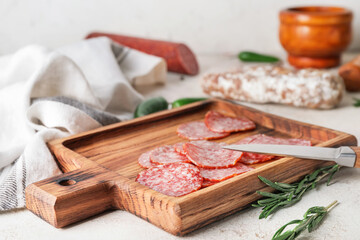 Board with slices of salami on table