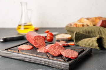 Board with tasty salami on table