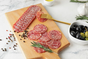 Board with tasty salami on light background