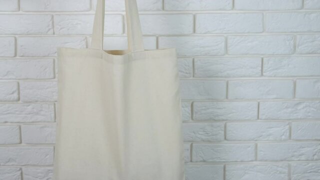 Food in eco bag. A woman show a white cotton shopper in her hand in the room.