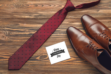 Male accessories with greeting card for Father's day on wooden background