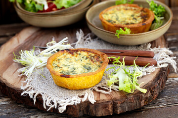 mini quiche com espinafre em uma placa de madeira, estilo rústico. 