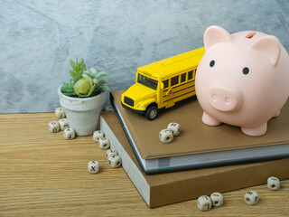 The school bus toy and piggy bank on wood table for back to school or education concept