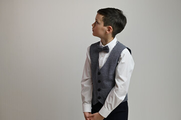 Portrait of cute teen boy in suit with bow tie on white background