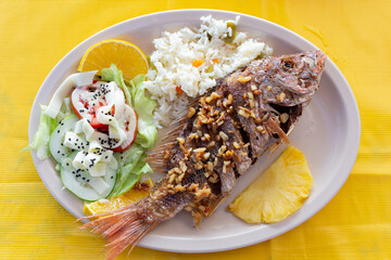 Plate of food with fried fish. Fried fish accompanied by vegetables and salad.