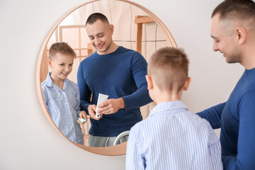 Father and little son brushing teeth in bathroom