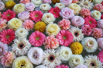 Flower arrangement of carnations, roses and gerberas. Pink, yellow and white flowers floating on the water.