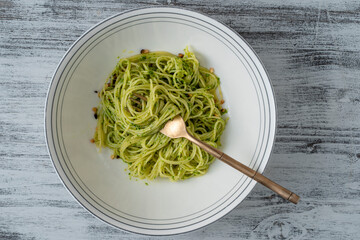 Spaghetti with green pesto sauce made with wild garlic, olive oil and pine nuts on a fork in plate, close up