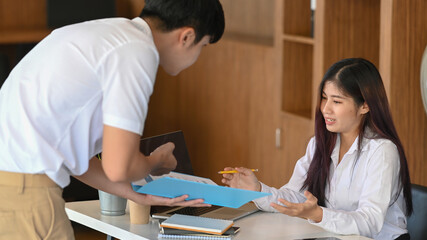 Obraz premium Two casual businesspeople analyzing financial report in modern office.