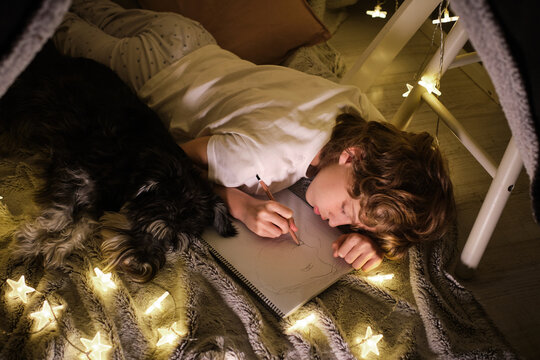 Focused Boy Drawing In Sketchbook In Blanket Fort