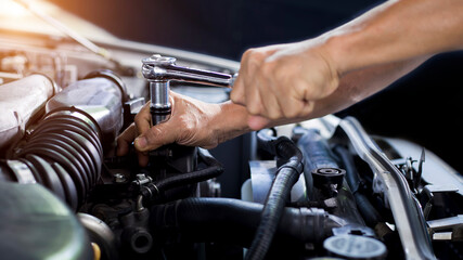 A car mechanic is doing a car repair in a repair shop.