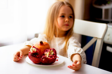 Little girl holding a pomegranate. Symbol of the Jewish New Year. Rosh ha Shana. Healthy organic sweet fruits. 