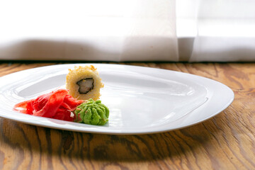 baked sushi with eel wasabi ginger on a white plate