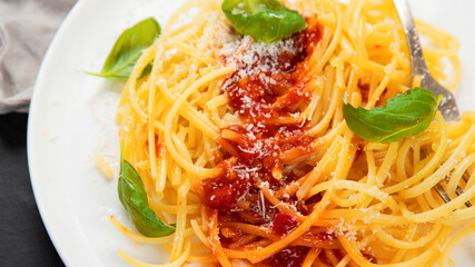 Delicious appetizing Italian pasta spaghetti with tomato sauce, parmesan and basil on a plate on a gray background. Top view, copy space