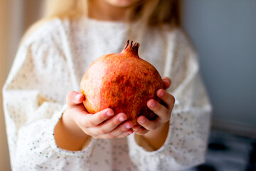 Little girl holding a pomegranate. Symbol of the Jewish New Year. Rosh ha Shana. Healthy organic sweet fruits. 