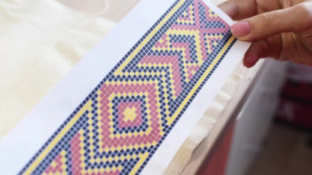 The process of embroidery with beads. Women's hands embroider a bead ornament. Painstaking handwork.