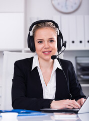 Friendly female helpline operator with headphones in call center