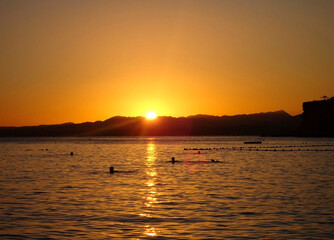 Beautiful sunset view and ocean view in the evening with people swimming in the water