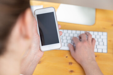 woman hands close up working on white computer keyboard and smartphone, work from home concept. work online, shopping