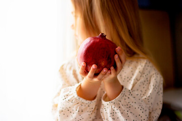 Little girl holding a pomegranate. Symbol of the Jewish New Year. Rosh ha Shana. Healthy organic sweet fruits. 