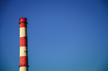 A red-and-white striped trumpet against a blue sky. Boiler room pipe. Production area