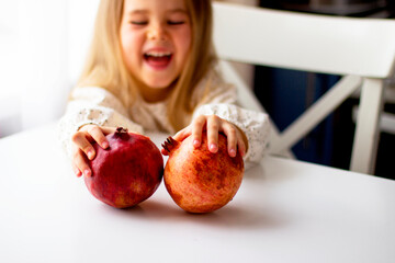 Little girl holding a pomegranate. Symbol of the Jewish New Year. Rosh ha Shana. Healthy organic sweet fruits. 