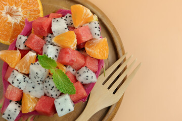 Tropical fruit salad with dragon fruit, watermelon and orange served in half a dragon fruit.