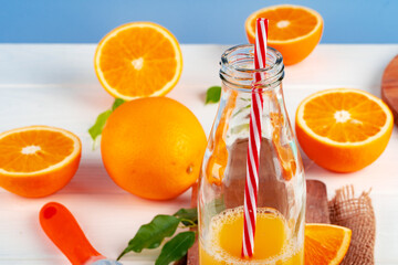 Bottle of orange juice and fresh oranges on table