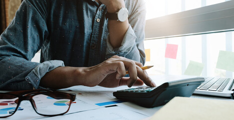 Business woman working in finance and accounting Analyze financial budget with calculator and laptop computer in the office