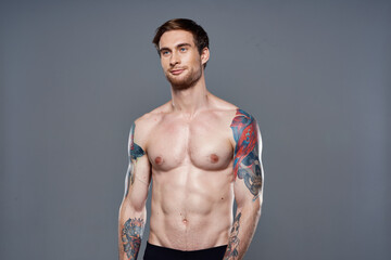 sporty man with a naked torso pumped up press tattoos on his arms