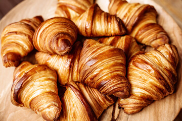 Fresh baked croissants. Warm fragrant butter croissants and rolls on a wooden stand. French and American pastries are popular all over the world.