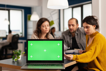Fototapeta premium Businesspeople analysing annual financial reports sitting at desk in back of laptop with green screen chroma key display, mock up desktop. Leader explainig project strategy using greenscreen pc