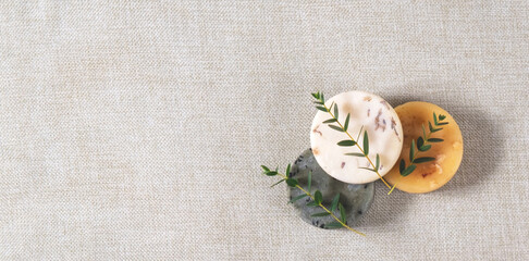 Fototapeta na wymiar The beautiful picture of the round natural handmade soaps with the twigs of eucalyptus on the cotton background with the copy space for your text. Zero waste concept of bathing without any package.
