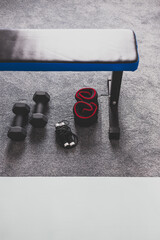 home gym with mixed fitness items including yoga mat abs bench weights and skipping rope