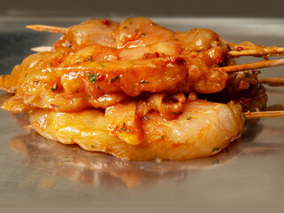 Marinated raw chicken pieces on a wooden skewer on a metal surface. Summer barbeque range product. Asian style sous over poultry meat. Ready made kebab