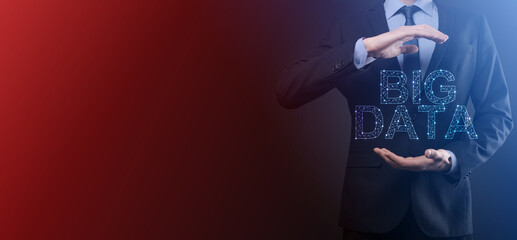 Businessman in a suit on a dark background holds the inscription BIG DATA. Storage Network Online Server Concept.Social network or business analytics representation