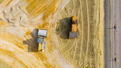Aerial view on two rollers as compacting fraction and sand over construction site for new traffic...