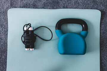 kettlebell and skipping rope on yoga mat indoor, concept of home gym and weight training vs cardio fitness